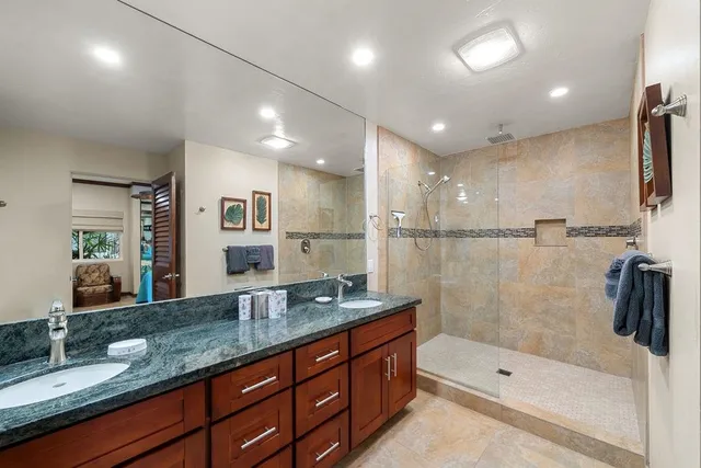 a bathroom with a granite countertop sink a large mirror and shower