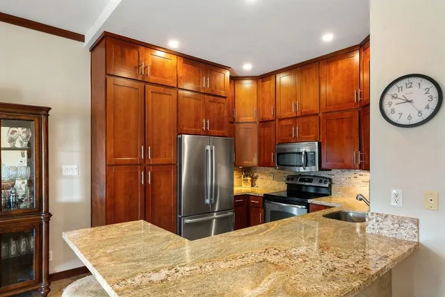 a kitchen with stainless steel appliances granite countertop a refrigerator a stove and a sink