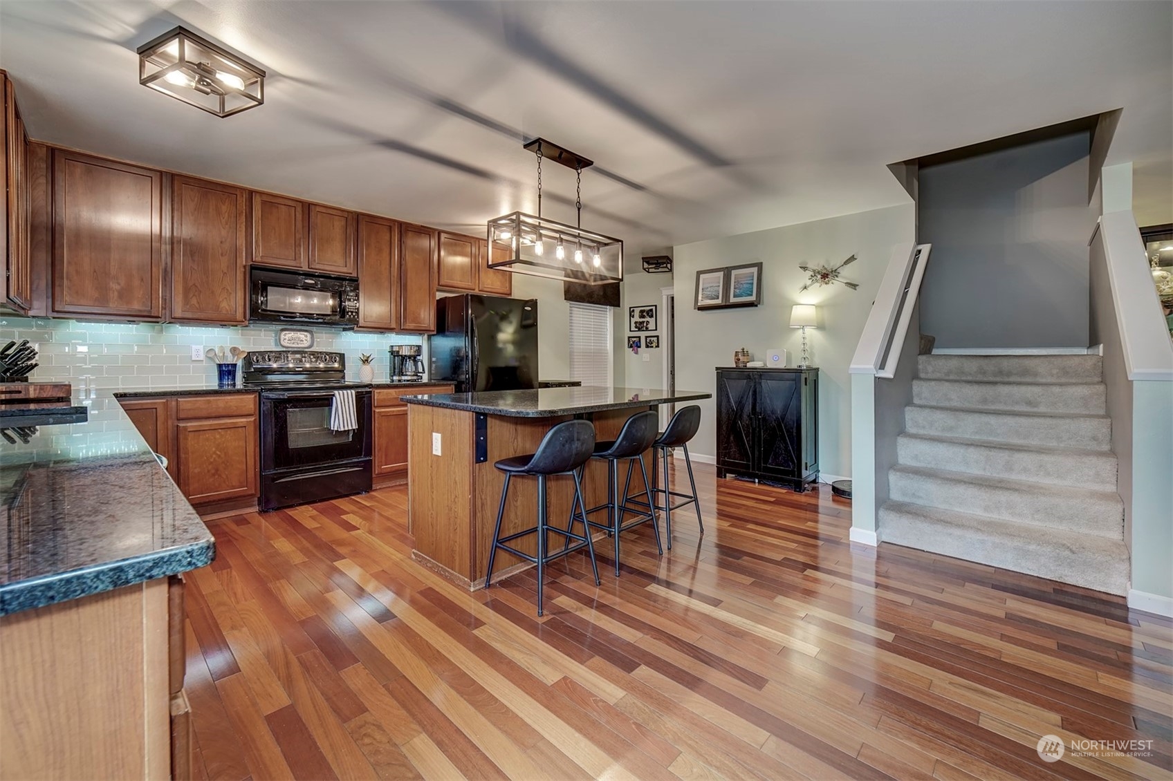 2195 Southwest Grebe Way Port Orchard, WA 98367 - Photo 12 of 40 a kitchen with stainless steel appliances kitchen island granite countertop a stove top oven a sink dishwasher a dining table and chairs with wooden floor