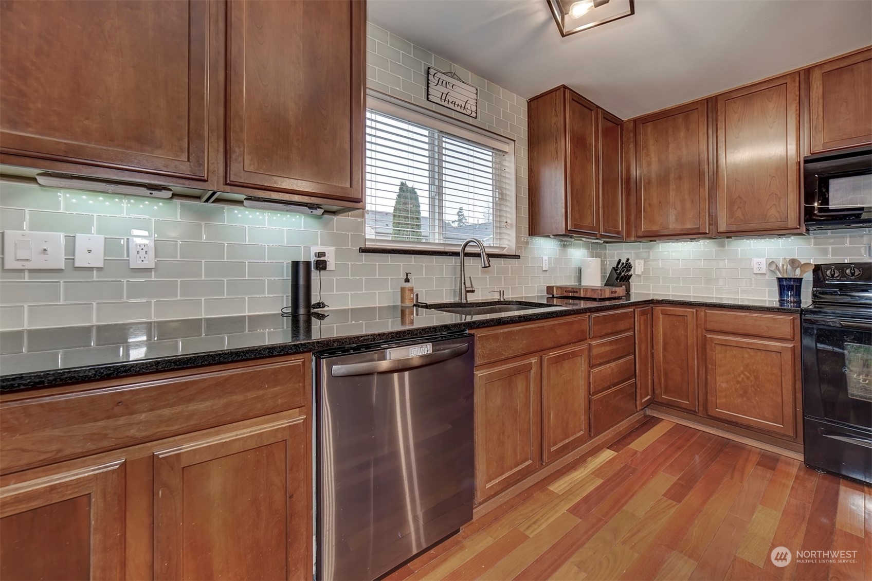 2195 Southwest Grebe Way Port Orchard, WA 98367 - Photo 14 of 40 a kitchen with granite countertop wooden cabinets stainless steel appliances a sink and wooden floor