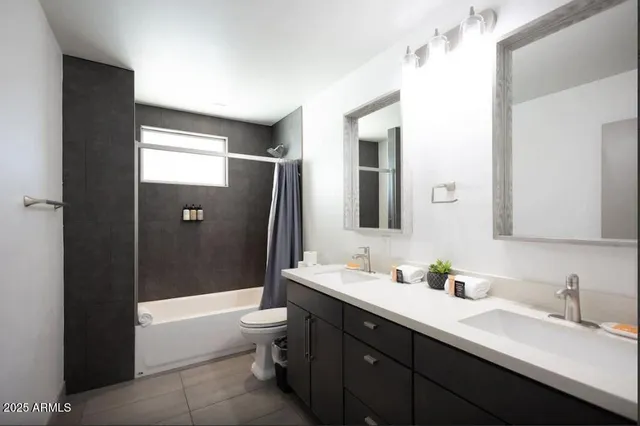 a bathroom with a double vanity sink toilet mirror and bathtub