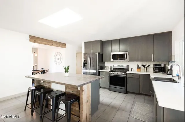 a kitchen with stainless steel appliances granite countertop a table chairs sink and cabinets