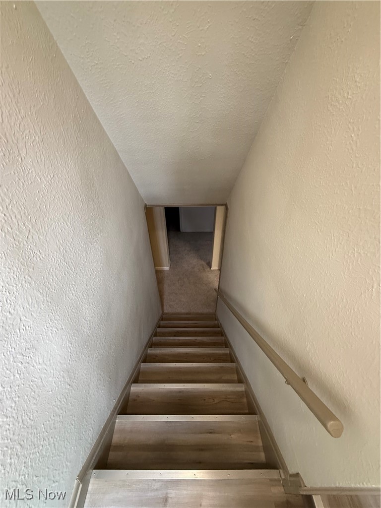 9417 Alexander Road Garfield Heights, OH 44125 - Photo 27 of 38 Staircase featuring a textured ceiling and a textured wall