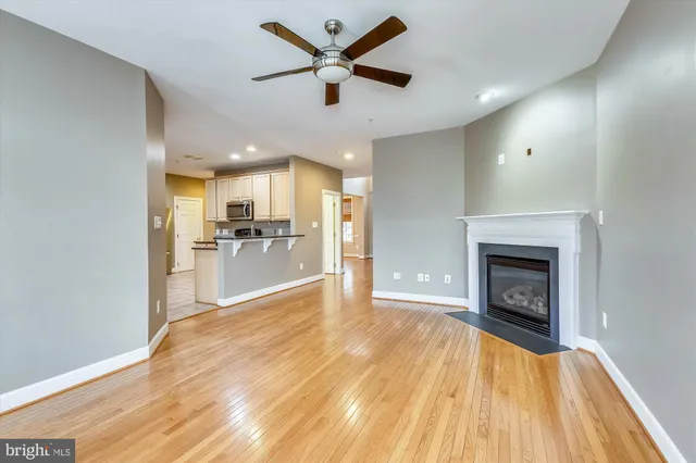 a view of a livingroom with a fireplace a ceiling fan and kitchen view