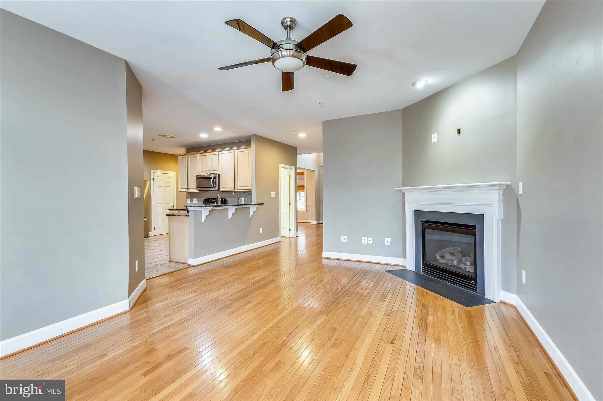 1004 Gaither Road Rockville, MD 20850 - Photo 11 of 34 a view of a livingroom with a fireplace a ceiling fan and kitchen view