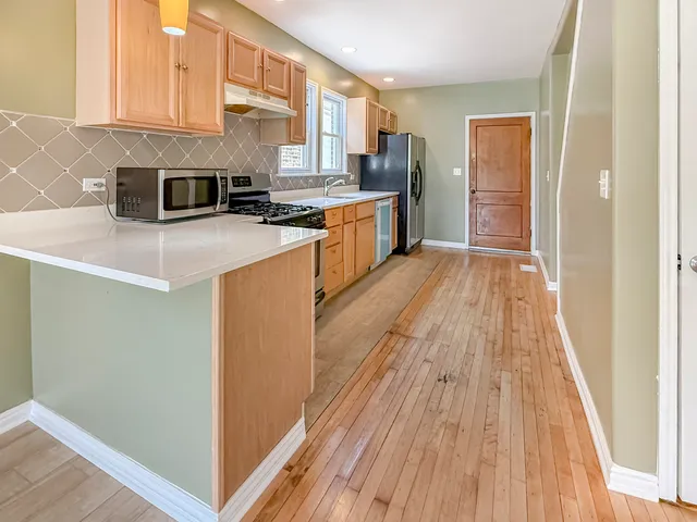 a kitchen with stainless steel appliances granite countertop a refrigerator a stove and a wooden floors