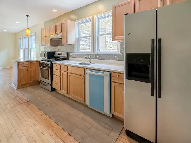 a kitchen with stainless steel appliances a refrigerator a sink a stove and white cabinets