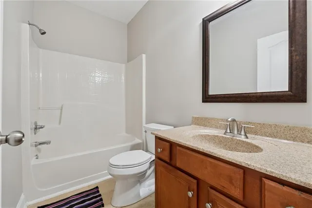a bathroom with a granite countertop toilet a sink and a bathtub
