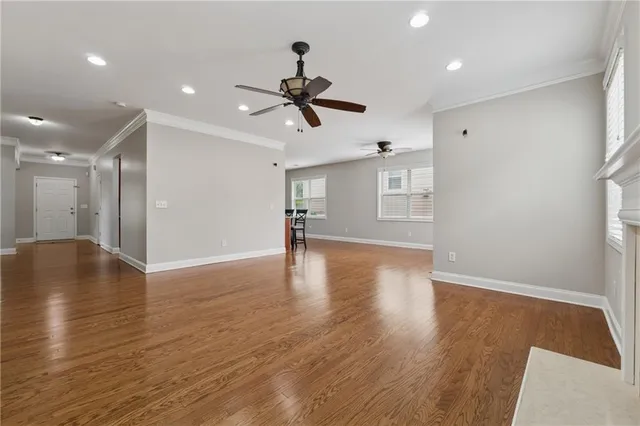 a view of empty room with wooden floor and ceiling fan