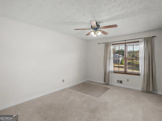 an empty room with a window and a fan