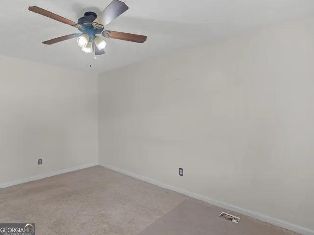 a view of an empty room and chandelier fan