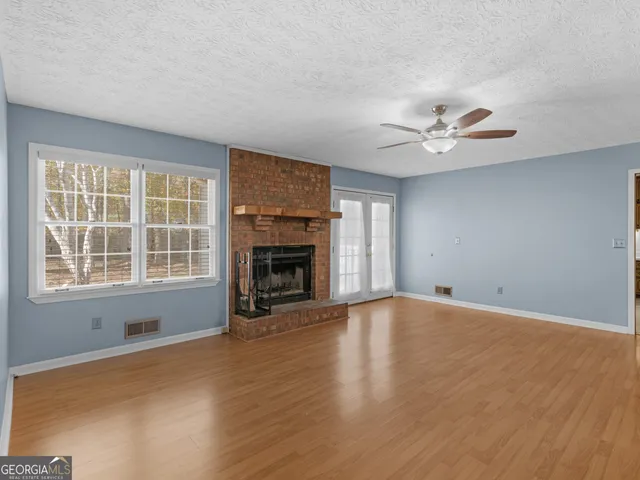 an empty room with windows fireplace and a sink