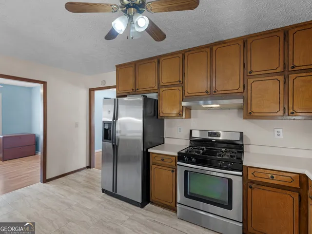 a kitchen with stainless steel appliances granite countertop a refrigerator a stove and a sink