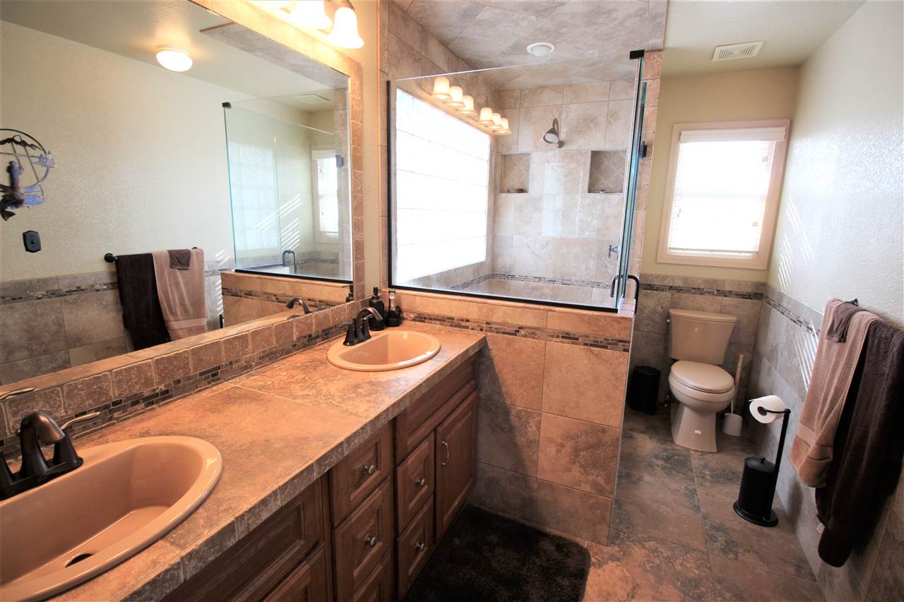 3455 F Road Clifton, CO 81520 - Photo 16 of 29 a bathroom with a granite countertop sink a toilet a mirror and shower