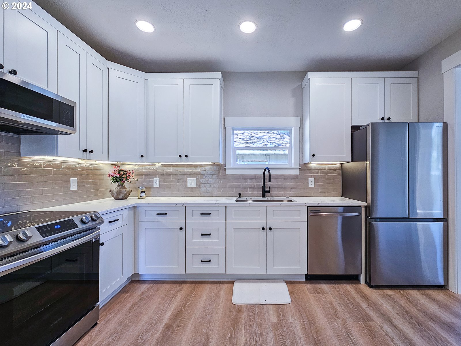 1532 Northeast Morgan Street Portland, OR 97211 - Photo 14 of 35 a kitchen with wooden floors white cabinets and stainless steel appliances