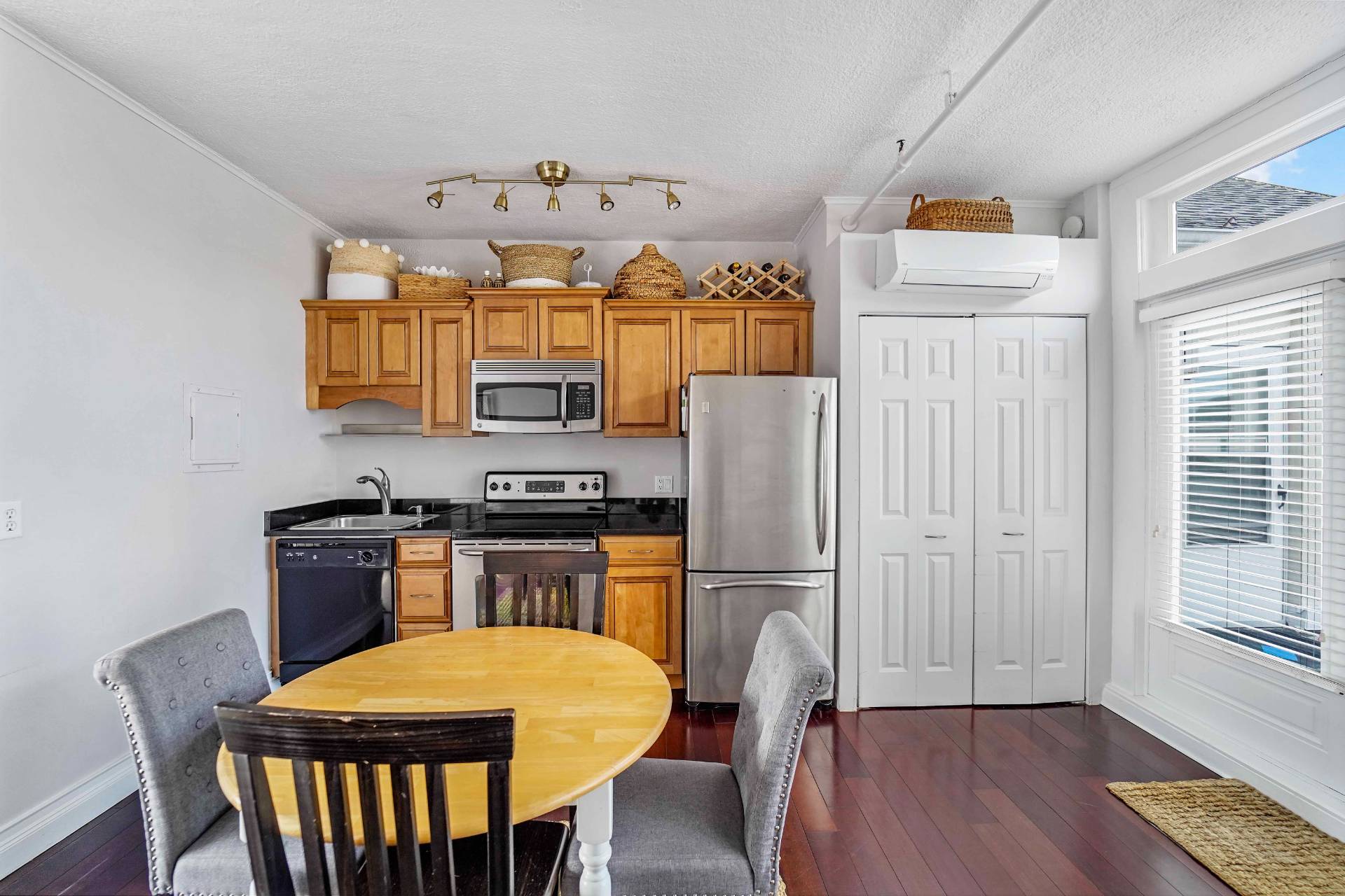 52 Main Street, Unit 1 Westhampton Beach, NY 11978 - Photo 6 of 13 a kitchen with stainless steel appliances a dining table chairs stove refrigerator and microwave