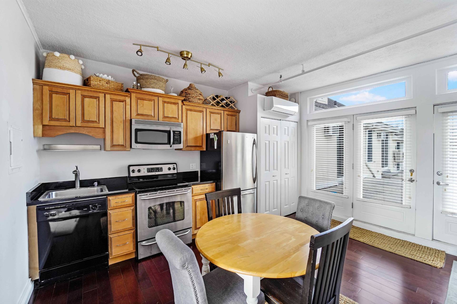52 Main Street, Unit 1 Westhampton Beach, NY 11978 - Photo 7 of 13 a kitchen with stainless steel appliances granite countertop a stove a refrigerator a kitchen island a dining table and chairs with wooden floor