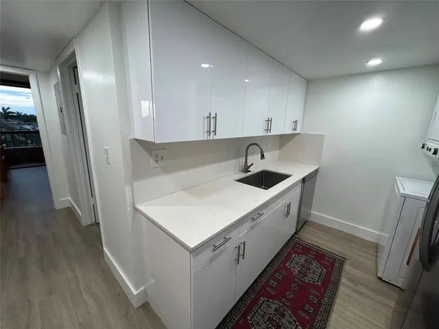 a kitchen with a sink a refrigerator and wooden floor