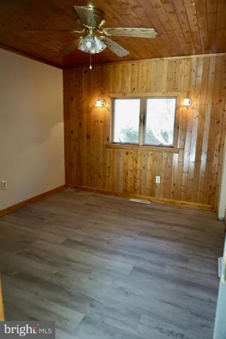 a view of an empty room with wooden floor and windows