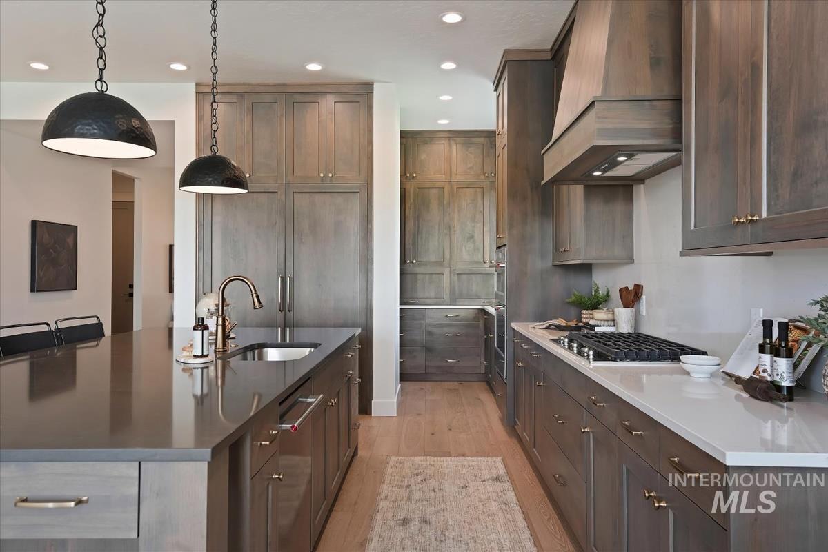 7615 Brown Way Eagle, ID 83714 - Photo 14 of 43 Kitchen featuring a large island with an undermount sink, built-in cooktop with a custom range hood, wood-finish flooring, and recessed lighting