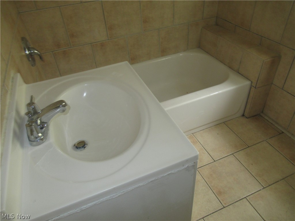 3824 East Antisdale Road Cleveland, OH 44118 - Photo 15 of 27 Bathroom featuring a white bathtub, integrated vanity sink with chrome faucet, and tiled walls with matching floor tiles