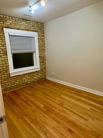a view of an empty room with wooden floor and a fireplace