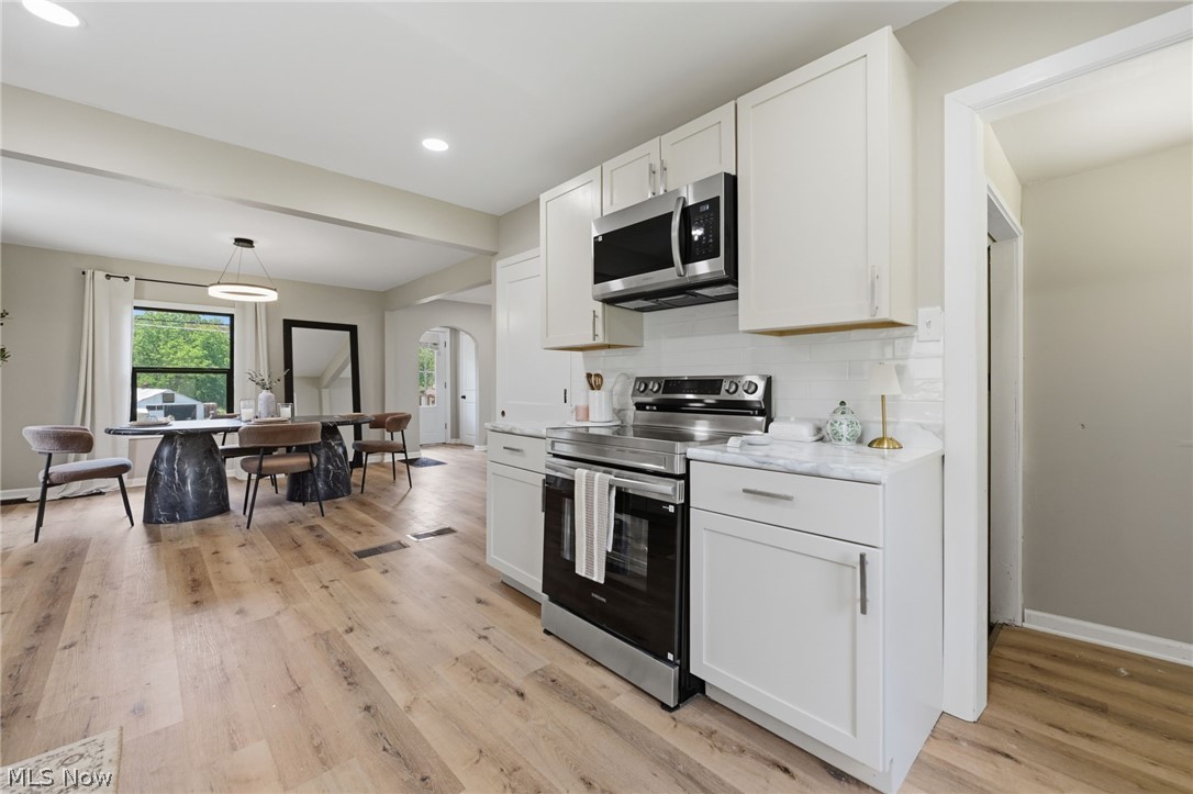 951 Bey Road Akron, OH 44312 - Photo 14 of 34 Kitchen featuring white cabinetry, stainless steel appliances, white subway tile backsplash, and light-toned wood-finish flooring