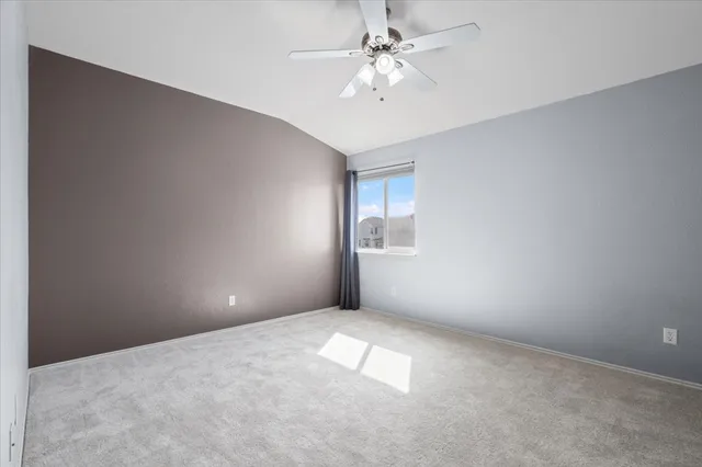 an empty room with windows and chandelier fan