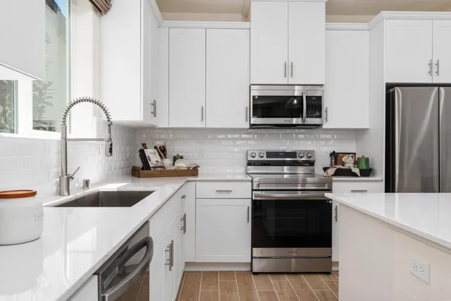 a kitchen with granite countertop a sink stainless steel appliances and white cabinets