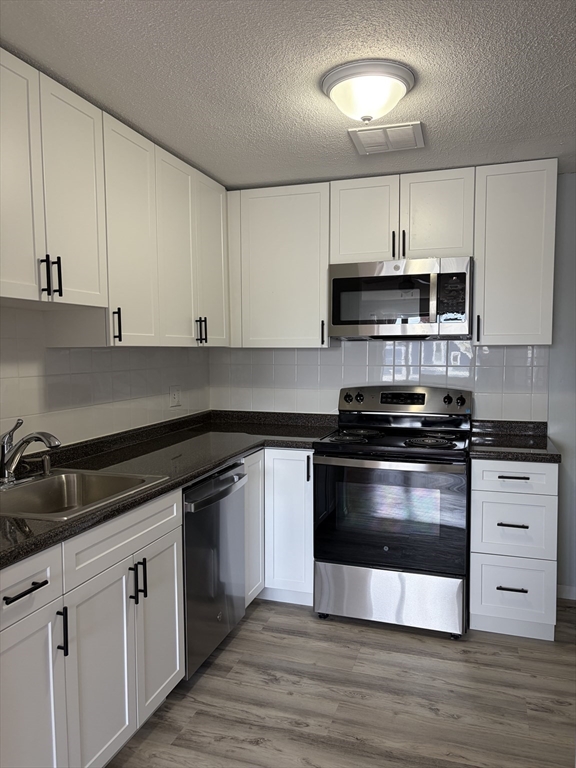 a kitchen with stainless steel appliances granite countertop a stove a sink and a microwave