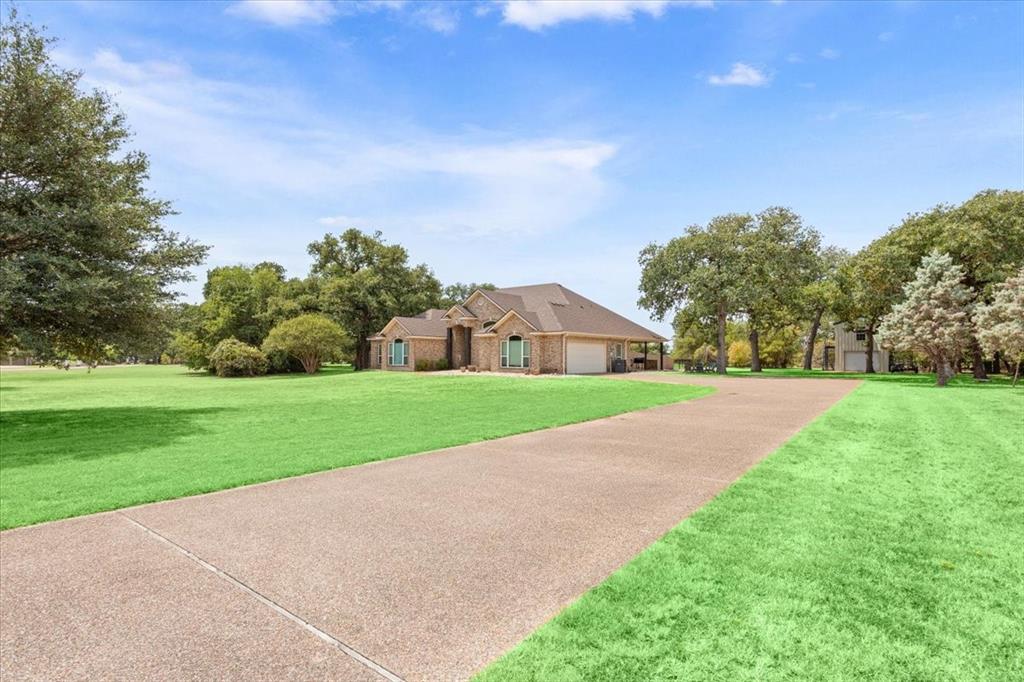 111 Spring Creek Street Waco, TX 76705 - Photo 3 of 40 Brick exterior with a multi-car garage, expansive lawn, mature trees, and a paved driveway