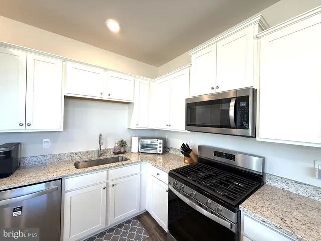 a living room with furniture kitchen view and a chandelier