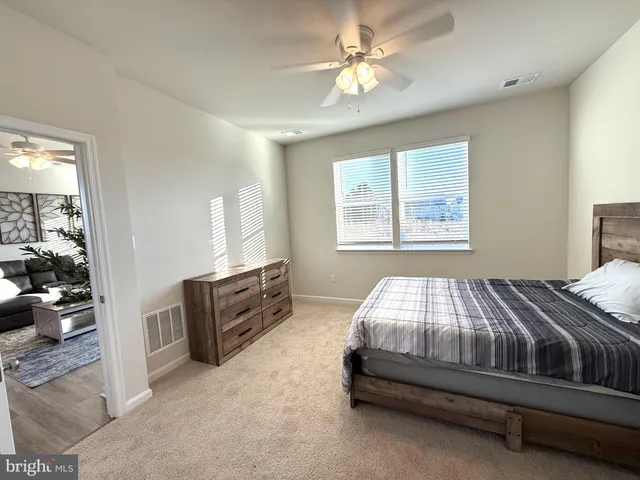 a spacious bedroom with a large bed a chandelier and windows
