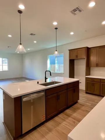 a kitchen with kitchen island granite countertop a sink a counter space appliances and cabinets