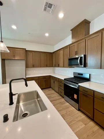 a kitchen with kitchen island granite countertop a sink and a stove top oven with wooden floor