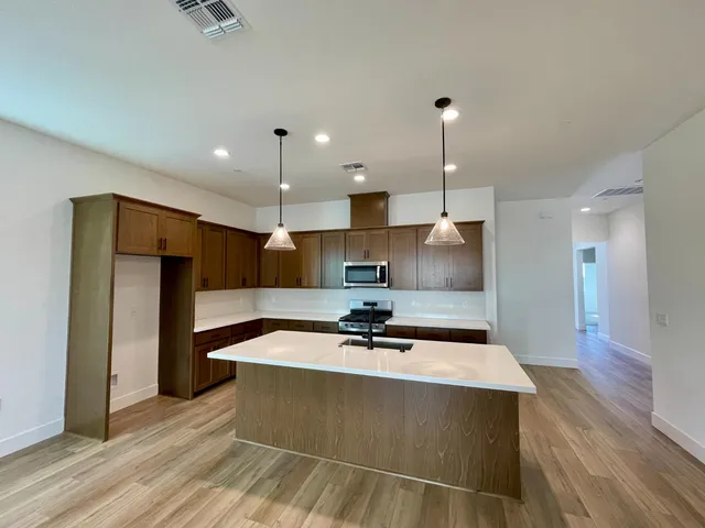 a kitchen with stainless steel appliances granite countertop a sink a refrigerator and a stove