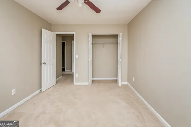 an empty room with closet and a ceiling fan