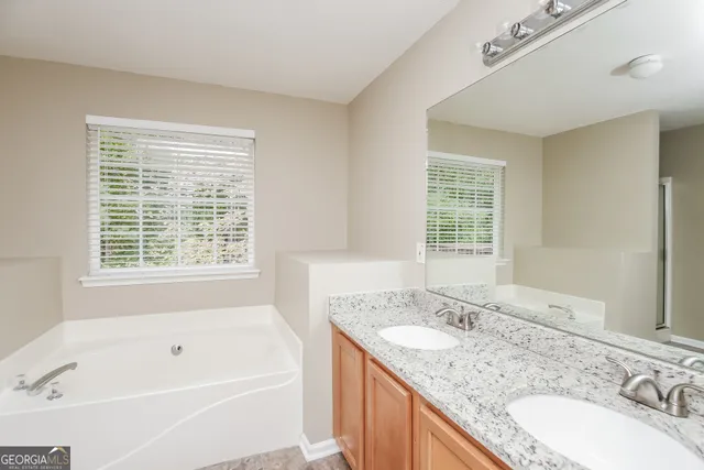 a bathroom with a granite countertop tub a sink and a window