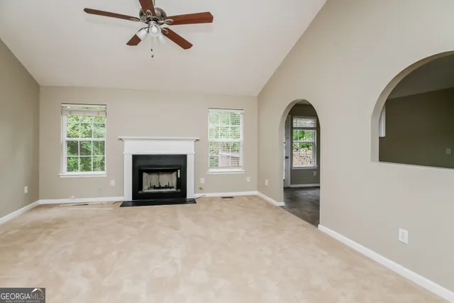 an empty room with windows and fireplace
