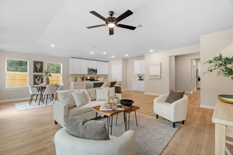 a living room with furniture kitchen view and a wooden floor