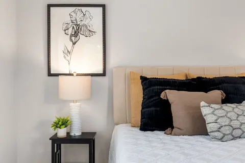 a bedroom with a bed and a lamp on dresser