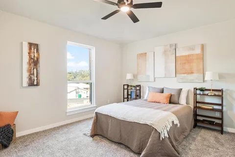 a bedroom with a bed next to a window and a chandelier