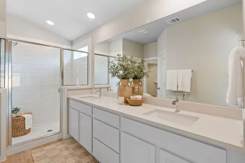 a bathroom with a double vanity sink mirror and shower