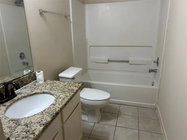 a bathroom with a granite countertop sink toilet and a mirror