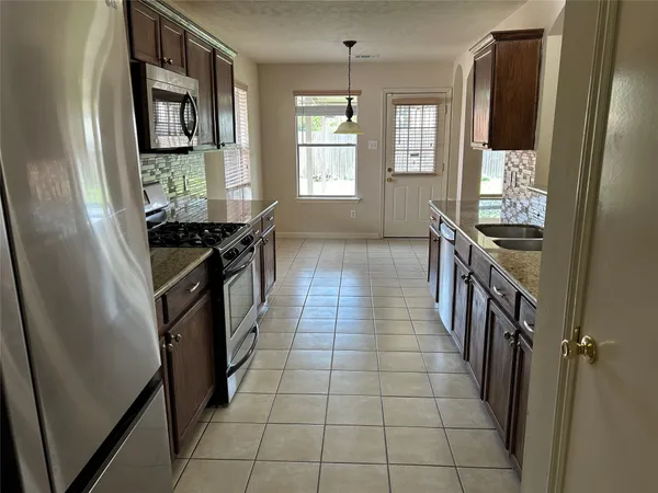 a kitchen with granite countertop a stove top oven sink and cabinets
