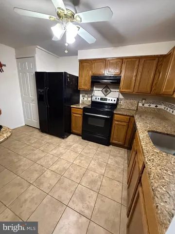 a kitchen with stainless steel appliances kitchen island granite countertop a refrigerator a stove top oven a sink and dishwasher