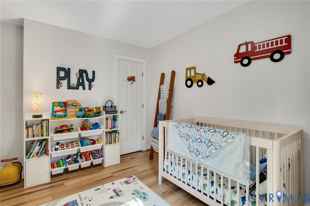 4990 Scandia Road Sandston, VA 23150 - Photo 17 of 25 a bedroom with baby crib and wooden floor