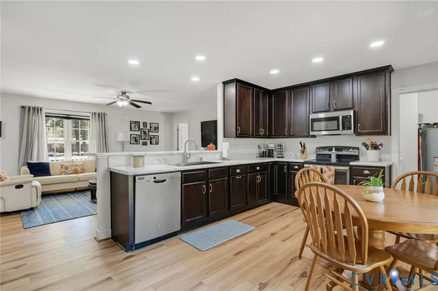 a kitchen with stainless steel appliances granite countertop wooden floors a stove a microwave a sink a refrigerator and cabinets