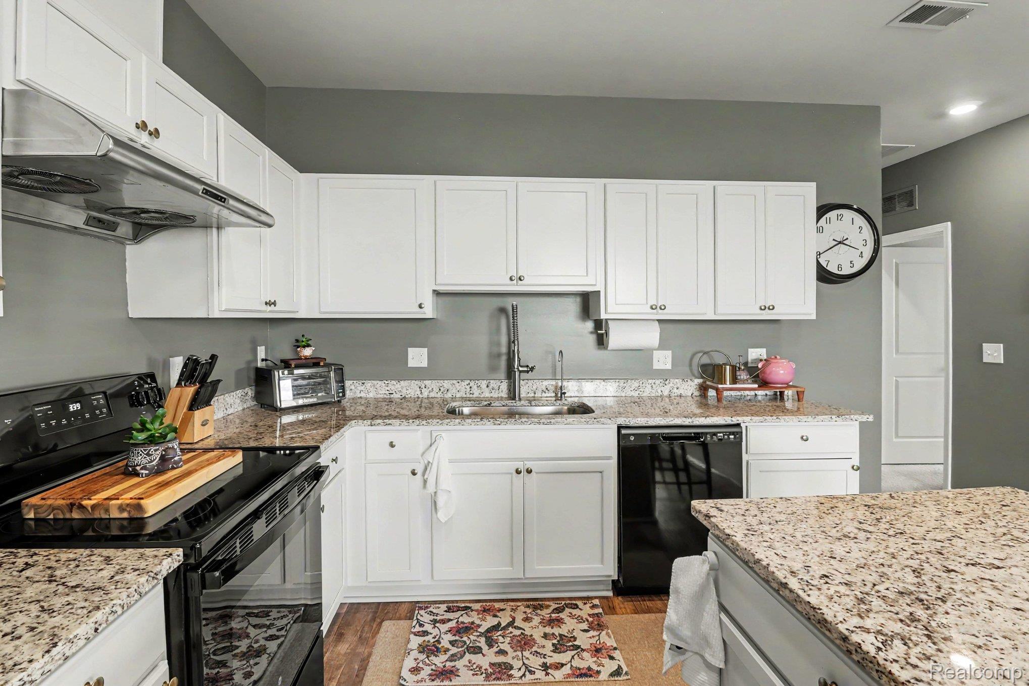 9864 Ridge Run Street Howell, MI 48855 - Photo 11 of 23 Kitchen featuring black appliances, white cabinets, light stone countertops, and light wood finished floors