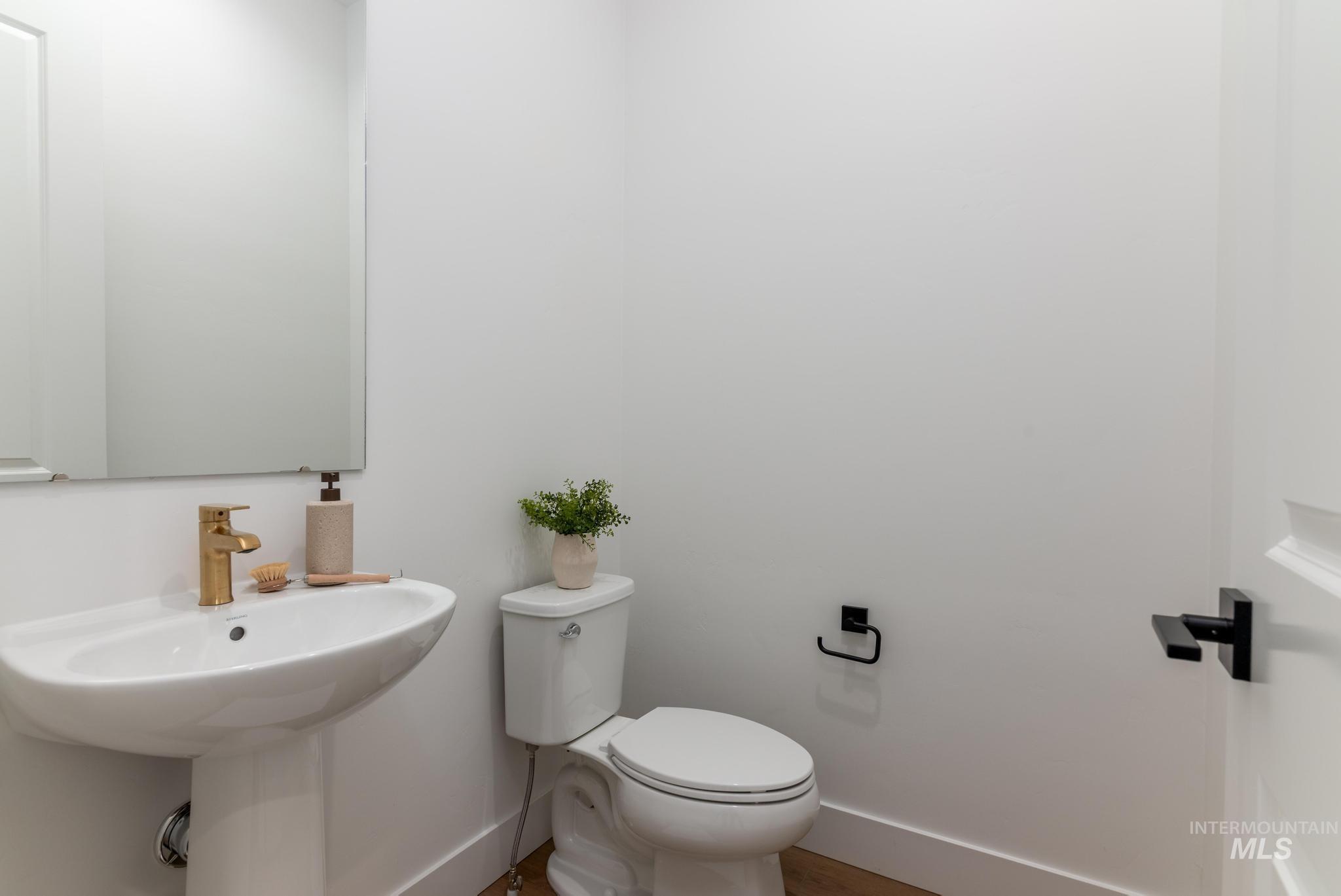 14703 Serenity Pt Street Caldwell, ID 83607 - Photo 22 of 45 Contemporary powder room featuring a pedestal sink with a gold-finish faucet, a rectangular wall-mounted mirror, and a modern toilet